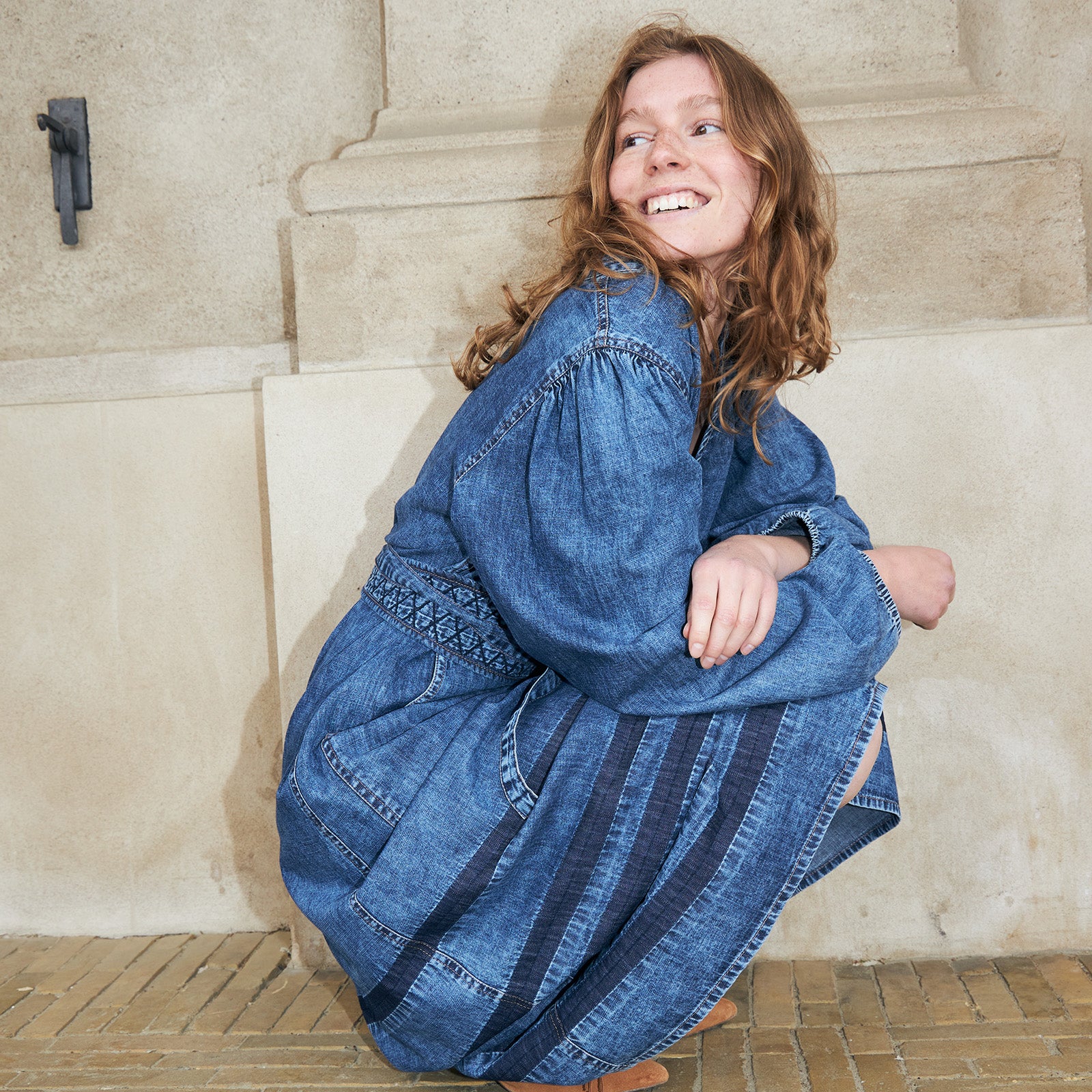 Kvinde iført blå denimkjole med broderede detaljer og vide ærmer. En afslappet og feminin denimstyle til hverdagen.